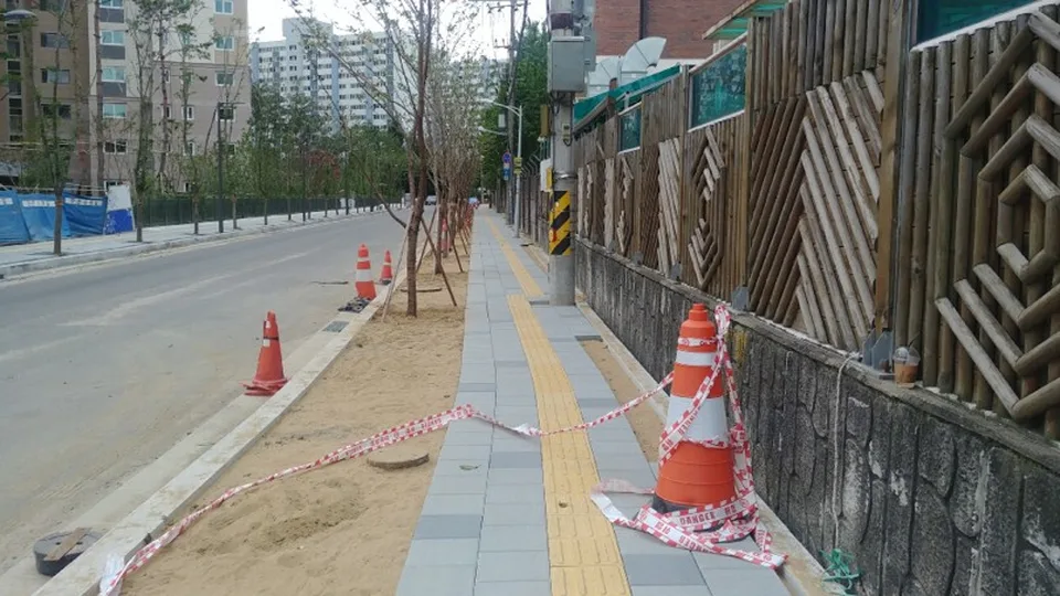 공사 자재와 라바콘이 보도를 막고 있는 거리 사진